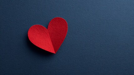 Obraz premium A red heart shape on a dark blue background with a textured surface