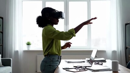 African american woman wearing vr headset interacting with virtual reality in a bright office setting - Powered by Adobe