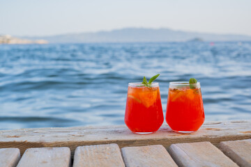 Two drinks on a wooden table by the sea