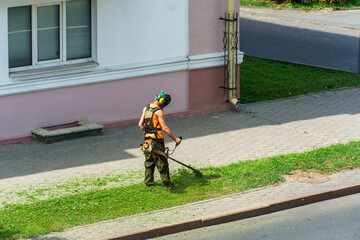 a man mows the grass. The lawn mower uses special equipment to mow the grass. A man in special protective clothing on the lawn.