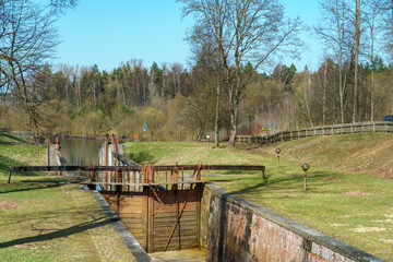 The old gateway gate on the canal. Wooden dam on the river. Autumn landscape.
