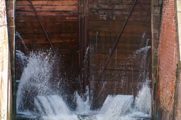 The old wooden gateway gate. The leaky lock gate on the canal. The leaking water is pressurized through holes and crevices.
