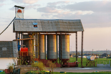 silver silos on agro manufacturing plant for processing drying cleaning and storage of agricultural products, flour, cereals and grain. Large iron barrels of grain. Granary elevator