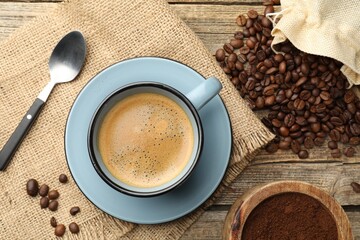Aromatic coffee in cup and beans on wooden table, flat lay