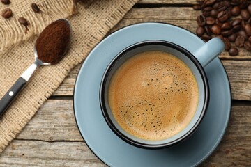 Aromatic coffee in cup and beans on wooden table, flat lay