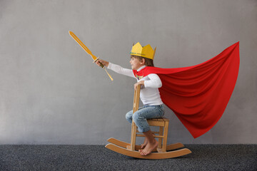 Funny child pretend to be knight. Happy kid having fun at home