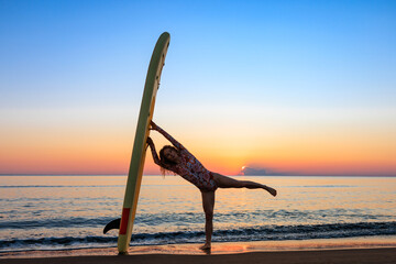 Young woman standing on beach with paddle sup boards during summer vacation