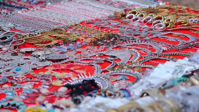 assorted colorful jewelry pieces displayed on red market cloth with vibrant beads stones and metal ornaments
