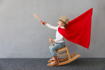 Funny child pretend to be knight. Happy kid having fun at home