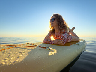 Young woman walking on stand up paddle sup boards by the sea during summer vacation