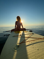 Young woman walking on stand up paddle sup boards by the sea during summer vacation