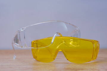 Pair of clear safety glasses on a wooden background highlights the importance of eye protection and workplace safety.