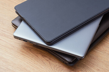 Close up view of stacked laptops on wooden surface. Concept of modern technology, corporate work, productivity and professional equipment.