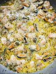 Mussels and shrimp cooking in creamy sauce