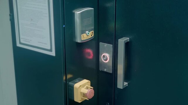 Emergency call unit for services if an elevator designed for people with disabilities and red emergency stop button are located next to the elevator door. Shot in motion