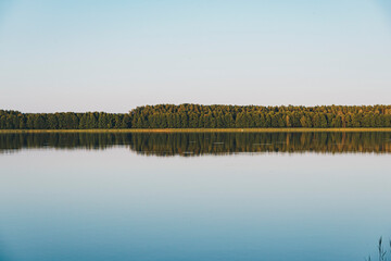 Fototapeta premium Landscape depicting a forest and its reflection in the calm waters of a lake