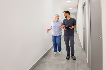 Senior woman and male ophthalmologist walking together and discussing eye treatment and medical guidance in hospital lobby
