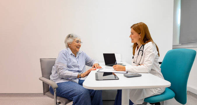 Female ophthalmologist writing diagnosis on clipboard while discussing health problems with senior patient in hospital - Powered by Adobe