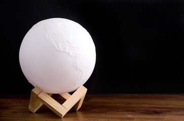 White Planet Globe Light on Wooden Table and Black Background