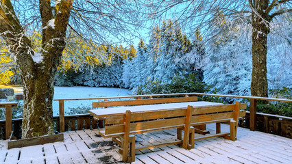 Winter Wonderland Snowy Deck with Wooden Table and Benches in a Forest Setting. Serene Scene
