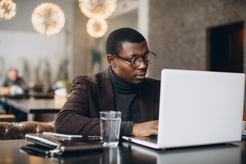 Focused young adult man working on laptop in cafe