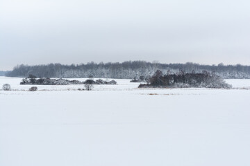 An extensive area of white snow blanket covers the landscape under a soft hazy sky.