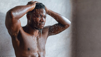 A man takes a shower, water cascading over his body. He stands with his hands on his head, focusing on his thoughts during his daily routine. This moment occurs in the morning.