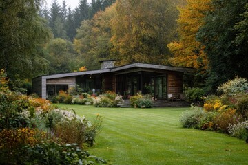 Obraz premium House in a forest with colorful trees and a green lawn during autumn, showing a cozy retreat surrounded by nature and plants