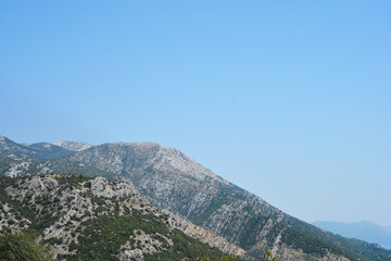 The rugged limestone peaks of Sveti Ilija na Peljescu rise sharply above the green Mediterranean macchia under a clear summer sky