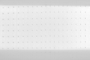 Close up macro shot of a white foam food container with a symmetrical pattern of small ventilation holes on a flat surface