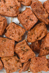 A top down macro view of cooked and seasoned vegan meat chunks made from soy protein showing fibrous texture and herbs