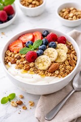Colorful yogurt bowl topped with berries, banana, granola, nuts, and mint on a bright table, perfect for promoting healthy breakfast, diet plans, or wellness blogs.