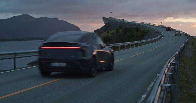 Cars driving on famous atlantic ocean road in norway at sunset