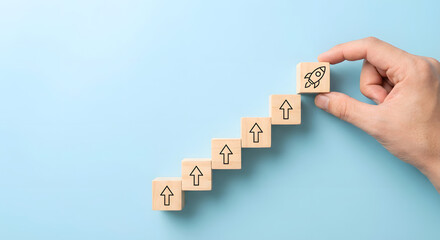 hand placing wooden block with rocket on ascending stairs