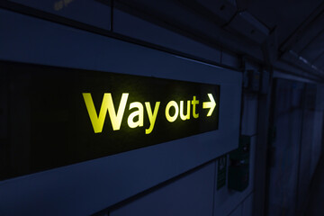 Way out sign glowing in dark underground station corridor