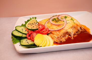 Imagen a detalle de una lasa&ntilde;a con queso y jutomate acompa&ntilde;ada de ensalada fresca