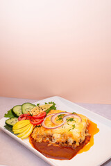 Plano vertical de un plato blanco de lasa&ntilde;a con ensalada 