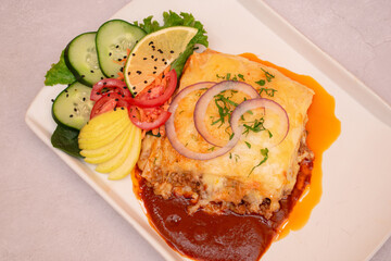 Plato de lasa&ntilde;a con queso y ensalada