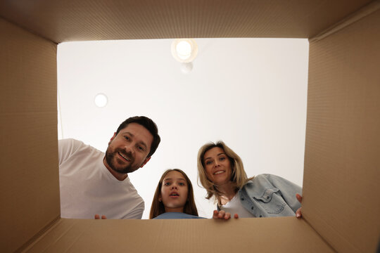 Excited family looking into cardboard box indoors, view from inside package