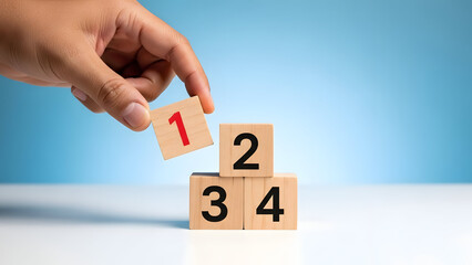 Hand placing wooden block with number on top of stacked blocks on table