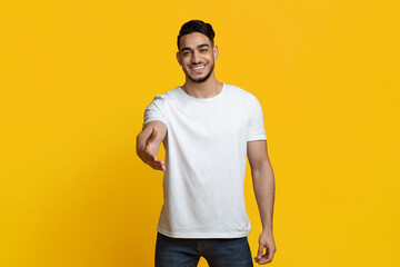 Nice to meet you. Charismatic handsome young arabic guy in casual outfit outstretching hand towards...