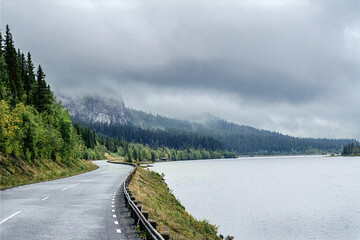 Winding road beside mountain lake on a cloudy day