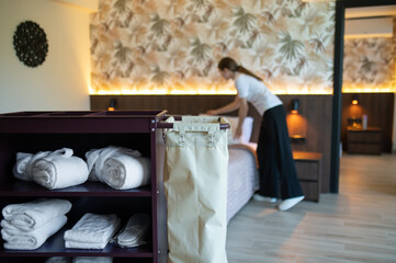 Young woman in a uniform tiding and changing linen in a hotel suit