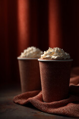Cozy Hot Chocolate Cups with Whipped Cream and Tweed Texture on Cinematic Red Curtain Background