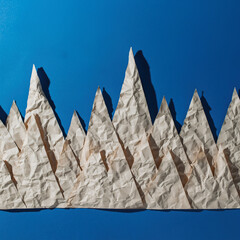 Crumpled paper forms a mountain landscape against a blue background displaying creativity and artistic design