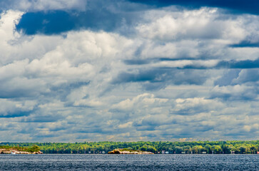 Threatening storm clouds towering over a sunlit treeline and two islands at Brockville on the St. Lawerence River