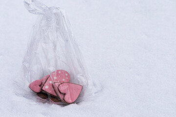Valentines gingerbread heart cookies wrapped in a clear bag placed on winter snow