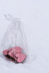 Festive gingerbread heart treats with pink glaze in transparent wrapping on snow.
