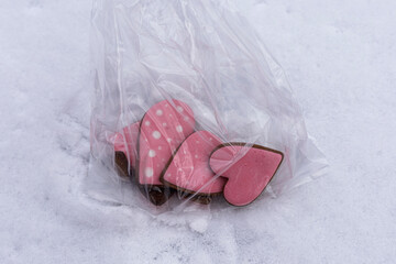Macro view of pink glazed gingerbread cookies wrapped in clear plastic on snow
