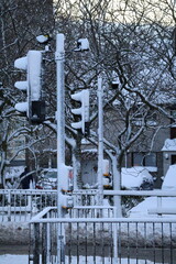 Traffic lights in pedestrian street crossing on snowing day.Urban buildings in the background .Traffic lights in pedestrian street crossing on snowing day.